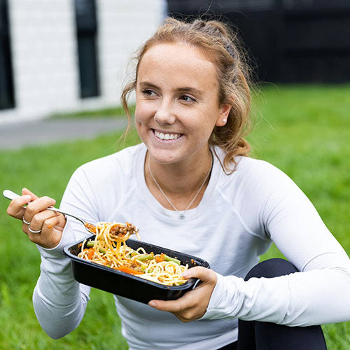 Woman eating delicious premade meal made that is delivered frozen ready to heat and eat by SwoleFoods based in Auckland New Zealand.